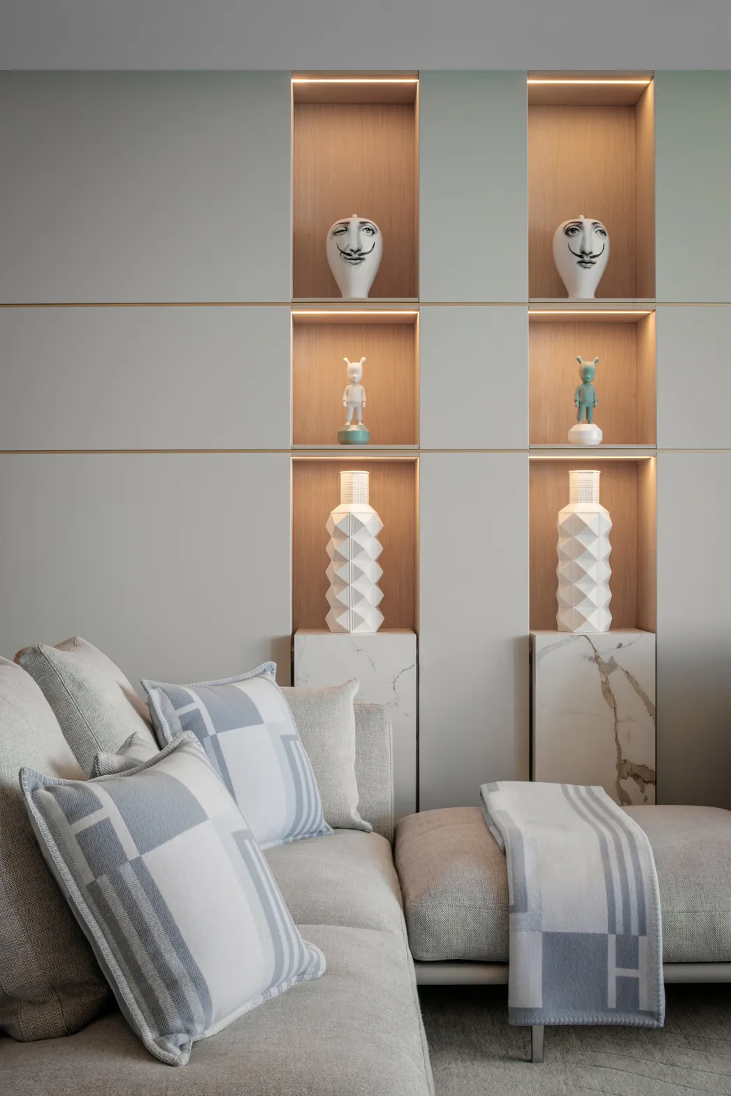 Living room wall niches in oak with integrated LED lighting and marble plinths above a linen sofa, Acqualina 2303, Sunny Isles Beach