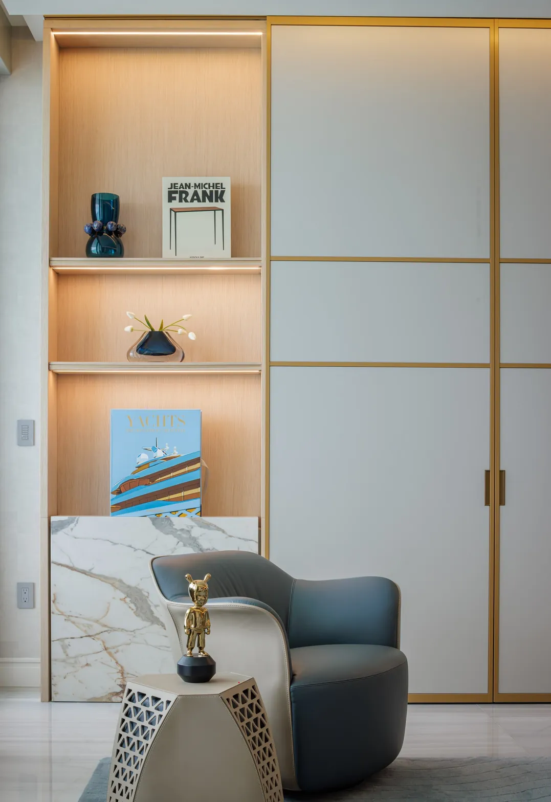 Living room corner with blue leather swivel armchair, lit oak shelving and brass-framed lacquer doors, Acqualina 2303, Sunny Isles Beach