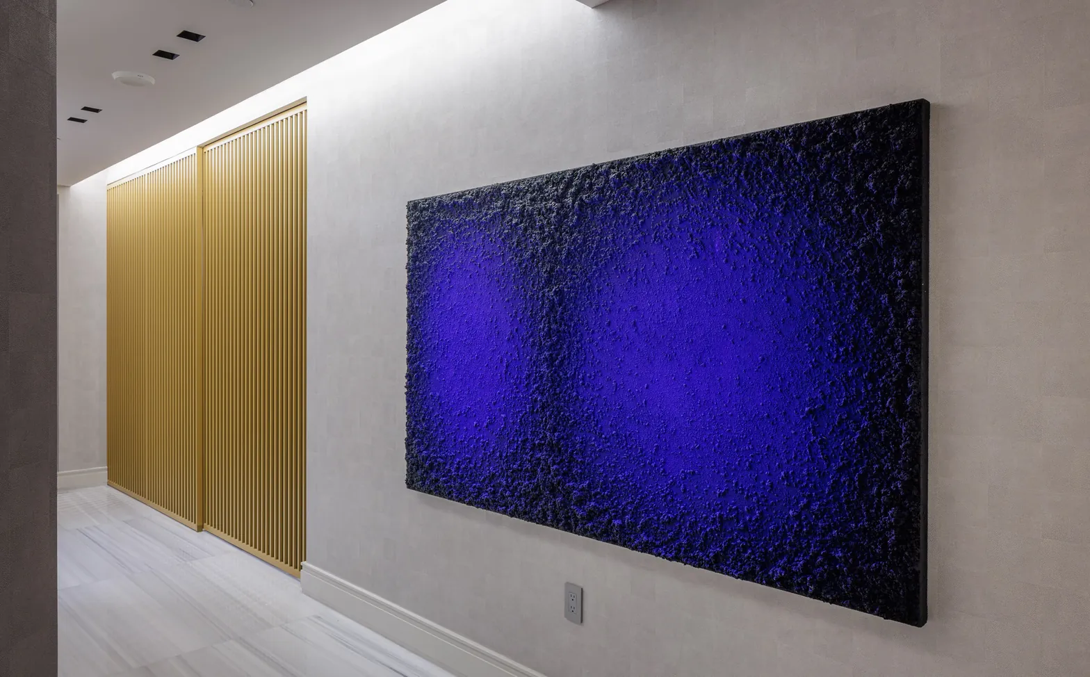 Hallway with Samuel Dejong textured blue artwork and brass slatted doors, Acqualina 2303, Sunny Isles Beach